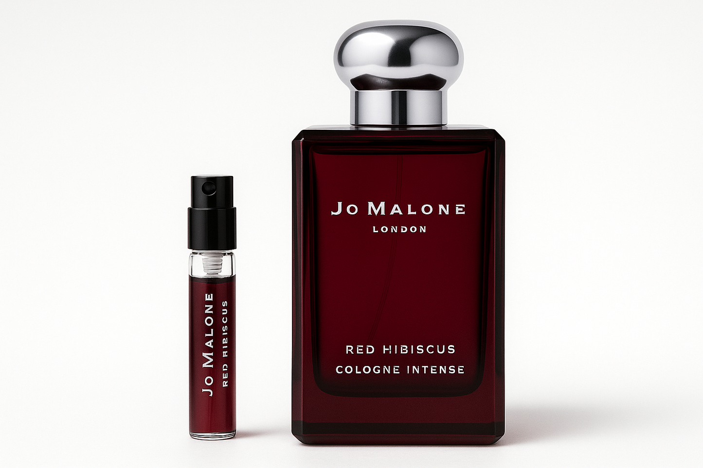 Jo Malone Red Hibiscus Cologne Intense 2 ml-prov bredvid en 100 ml parfymflaska med Jo Malone Red Hibiscus Cologne Intense som har vit text på den mörkröd flaskan.