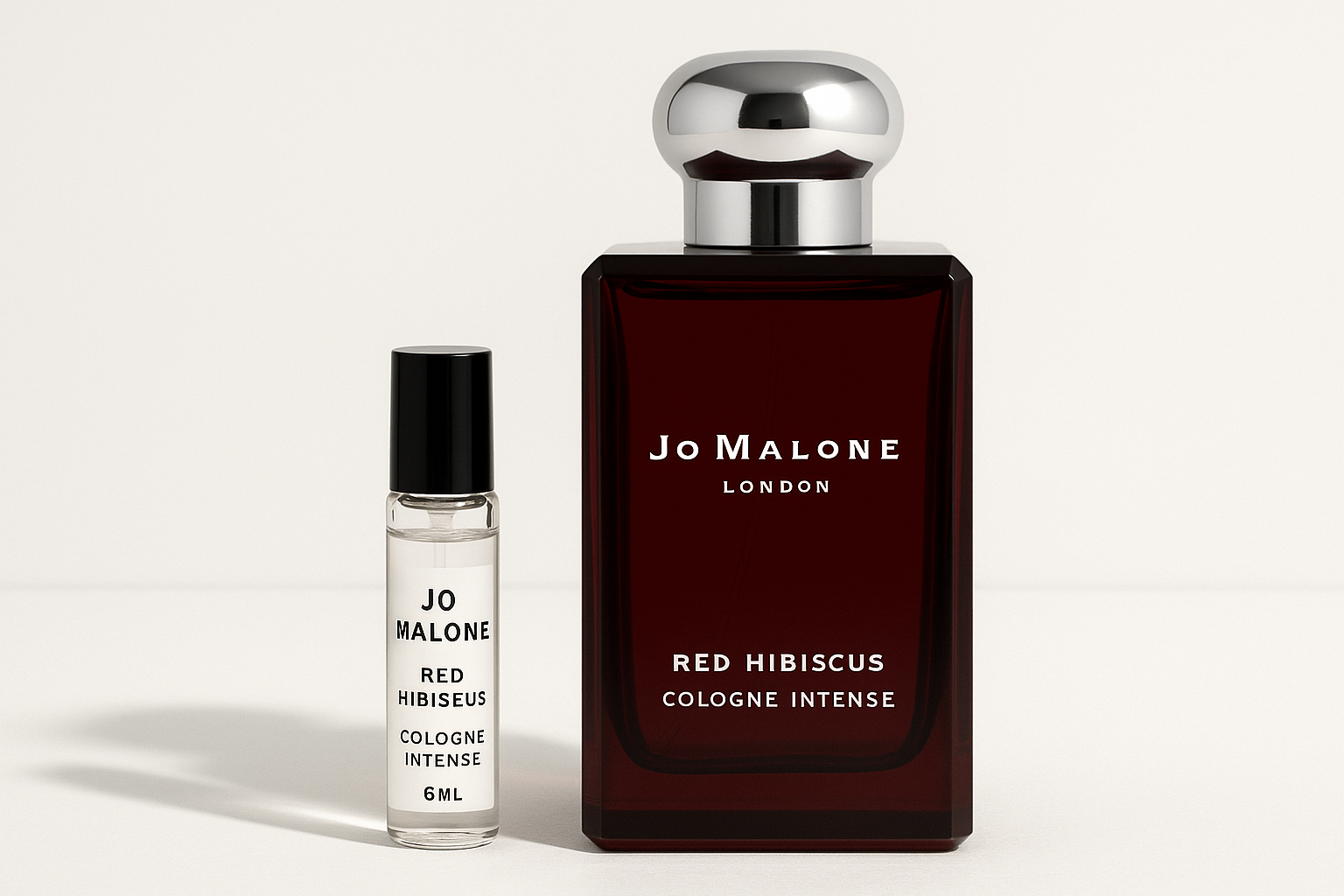 Jo Malone Red Hibiscus Cologne Intense 6ml-prov bredvid en 100ml parfymflaska med Jo Malone Red Hibiscus Cologne Intense som har vit text på den mörkröd flaskan.